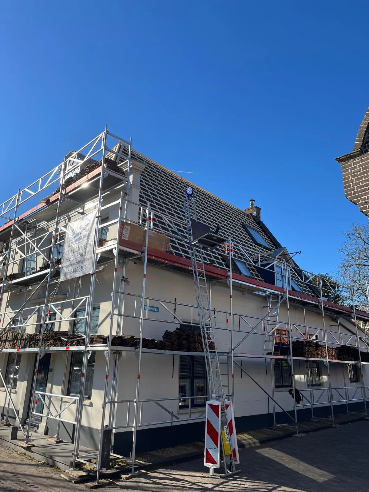 Dakrenovatie met steigers rondom een woning met hellend pannendak in Edam, Noord-Holland