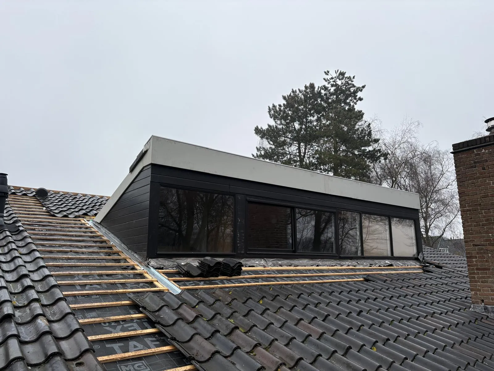 Grote moderne dakkapel met donkere bekleding op een hellend dak in Heiloo, Noord-Holland