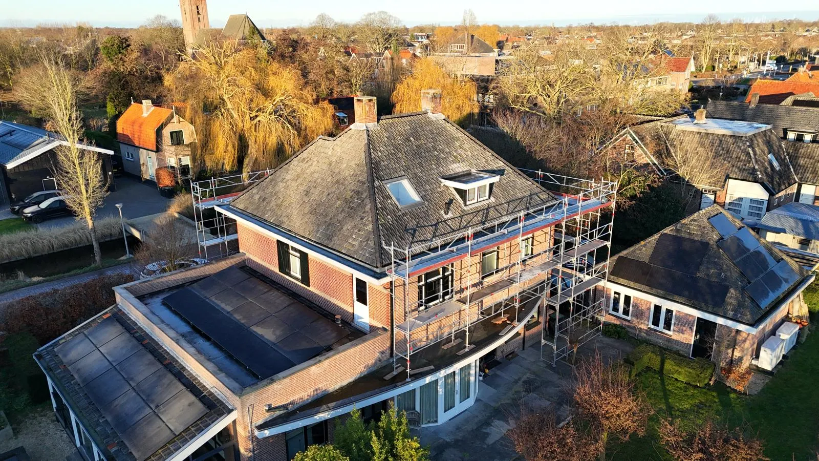 Renovatie van een hellend pannendak met steigers rondom een woning in Noord-Holland