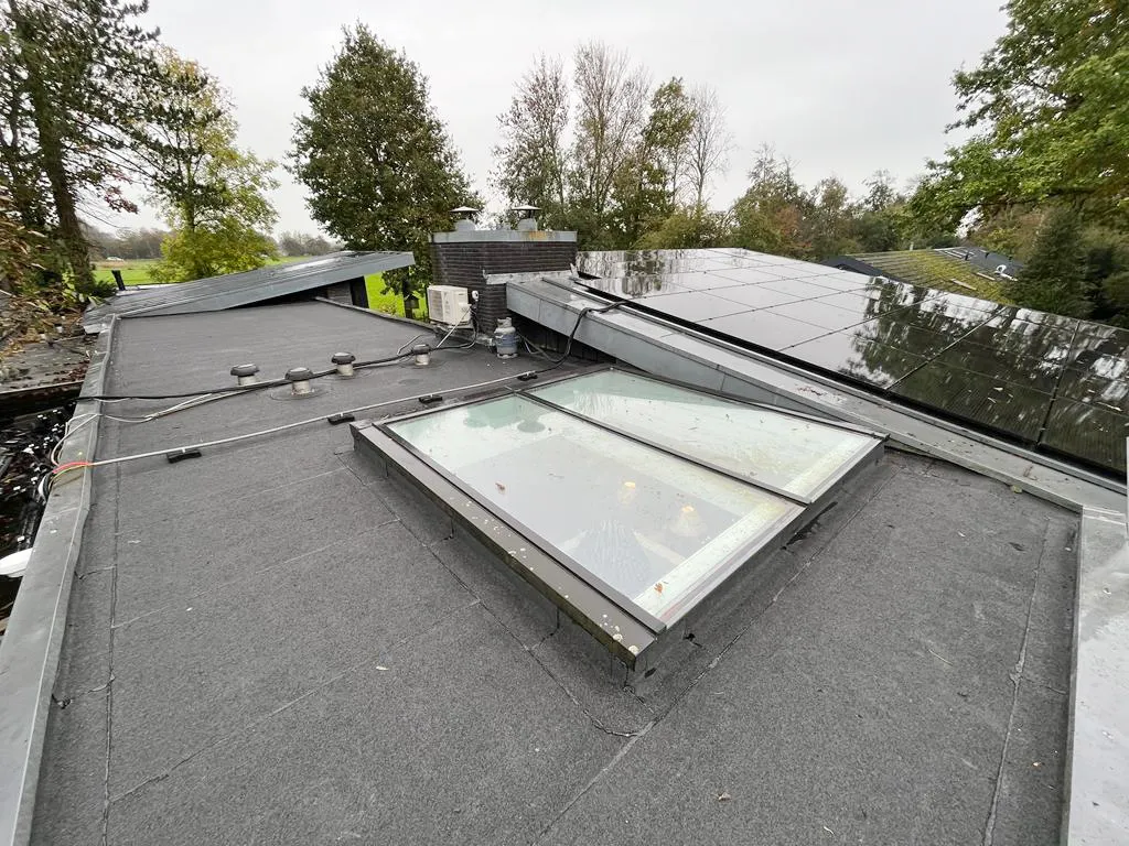 Plat dak met lichtkoepel en zonnepanelen op een villa in Bergen Noord-Holland