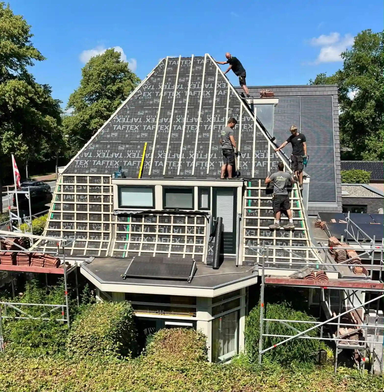 Dakdekkers van NH Dakwerken brengen dampopen onderdakfolie en nieuwe panlatten aan op een pannendak in Heiloo