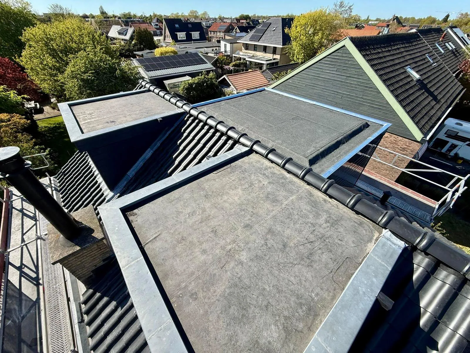 Twee vernieuwde platte daken met zinken randafwerking in Limmen