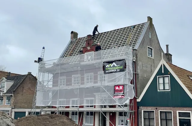 Dakrenovatie van een rijksmonument met steigers en zichtbare daklatten in Edam