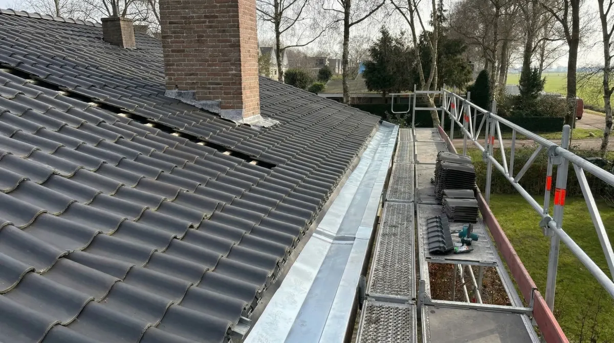 Zinken dakgoot en loodwerk rond een schoorsteen op een pannendak van NH Dakwerken